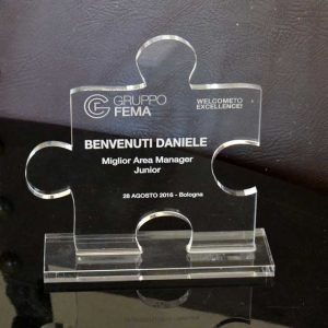 Targa plexiglass sagomata su piedistallo Trofeo premiazione Area Manager gruppo FEMA, forma di puzzle, in 10 mm, con marcatura laser