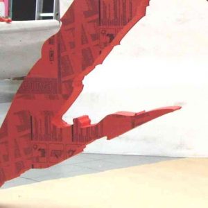 Insegna a logo PVC gigante rossa  In PVC massello realizzata in una lastra intera fresata, destinata ad essere appesa in aria su uno stand.